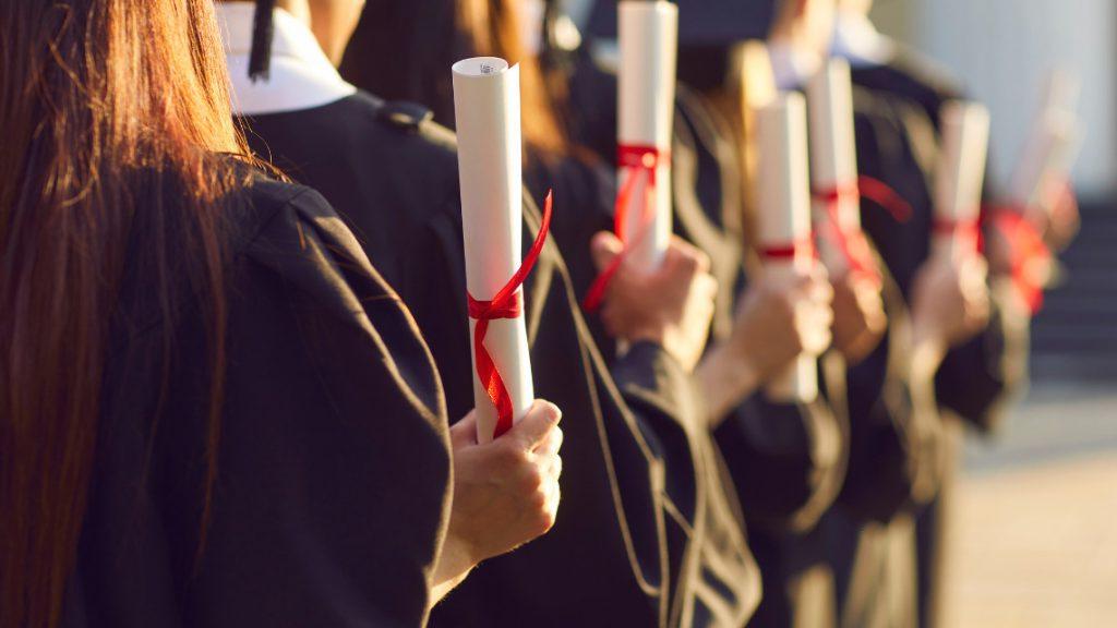 Row of graduates holding diplomas for article on starting salaries