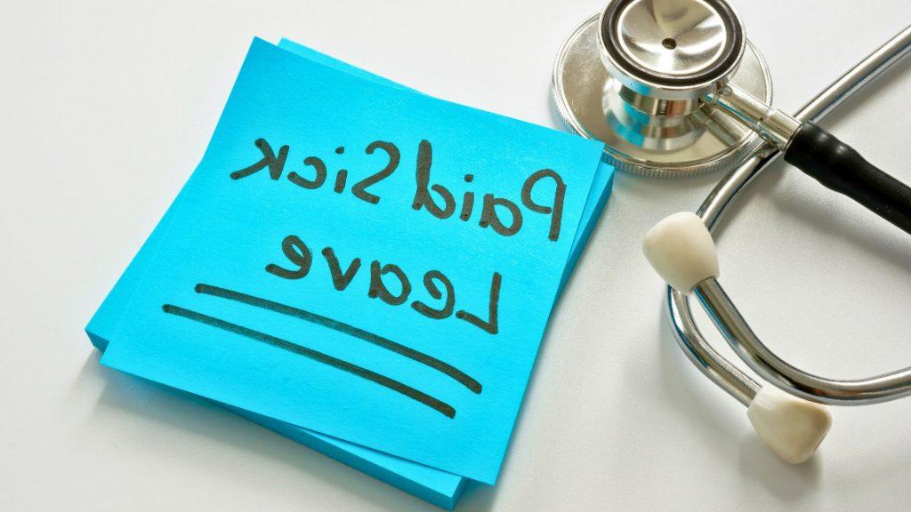 the words 'paid sick leave' written on a post-it sitting next to a stethoscope